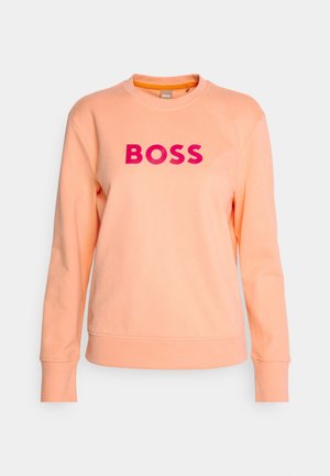 Peach sweatshirt with crew neckline and long sleeves. Features bold pink "BOSS" lettering on the front. Made from soft, textured fabric.