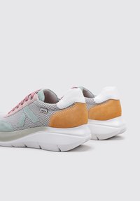 Zapatillas de tela con parte superior de malla, con acentos en ante rosa, azul claro y beige, talón blanco y suela blanca acolchada.