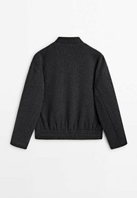 Veste en tissu texturé gris foncé avec un col, un ourlet élastique et des manches longues, présentant un design épuré et simple.