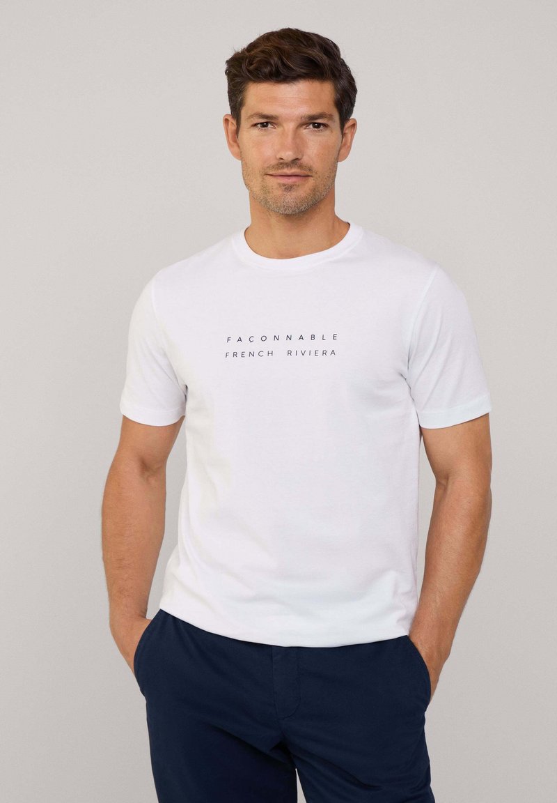 Witte katoenen T-shirt met een ronde hals en korte mouwen, met een donkere opdruk van de tekst "FACONNABLE FRENCH RIVIERA" op de voorkant.