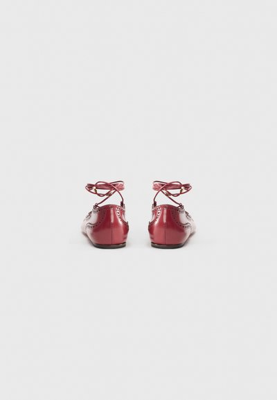 Czerwone baleriny z miękkiej skóry z zaokrąglonym noskiem, perforowanymi zdobieniami oraz regulowanymi tasiemkowymi sznurowadłami. Gładkie wykończenie i płaska podeszwa.