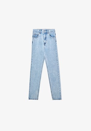 Top corto de mezclilla en azul claro con un diseño bordado, combinado con jeans de tiro alto en azul claro. La modelo lleva sandalias de tacón grises.