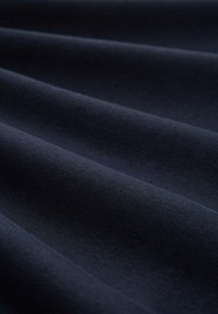 Tejido de un navy oscuro con una textura suave y lisa, que presenta sutiles ondulaciones. El material parece ligero y está tejido de manera uniforme sin patrones.