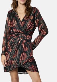 Robe noire à manches longues, dotée d'un motif floral avec des accents rouges et dorés, présentant un design enveloppant et une taille froncée.