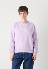 Lilla crewneck sweatshirt med en subtil Calvin Klein-logo i midten. Myk tekstur, lange ermer og ribbestrikkede mansjetter og kant.