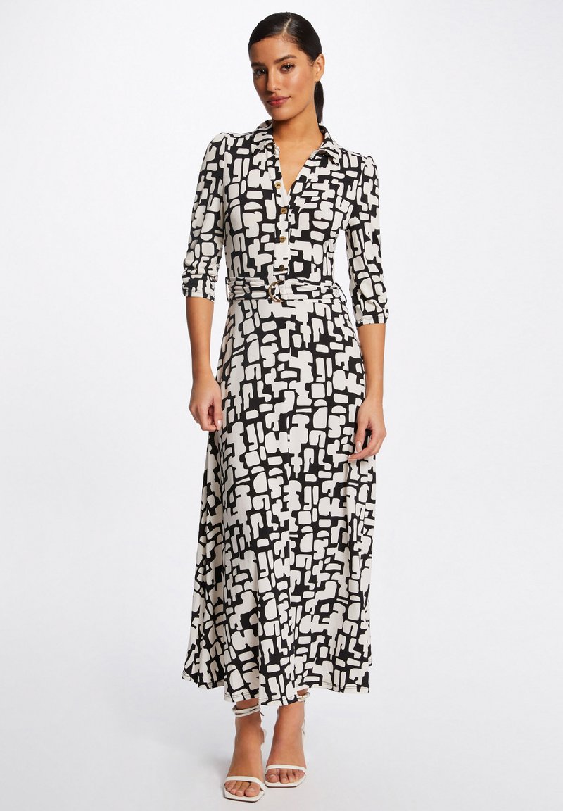 Schwarz-weißer gemusterter Kleid mit Kragen, drei Viertel langen Ärmeln und einem Bindegürtel in der Taille. Glatter Stoff und Knöchellänge.