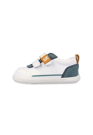 Zapatilla para niño pequeño en blanco y verde azulado con dos correas de velcro, lengüeta de tirador marrón claro y suela blanca perforada, mostrada sobre un fondo blanco.