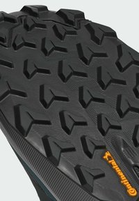 Schwarze Gummisohle mit tiefen, multidirektionalen Profilmustern und konturiertem Textur. Mit einem gelben Akzent des "Continental"-Logos.