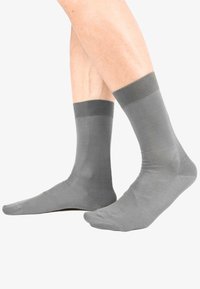 Calze grigie realizzate in un materiale liscio, con un polsino a coste. Il design è a lunghezza caviglia e presenta una punta senza cuciture.