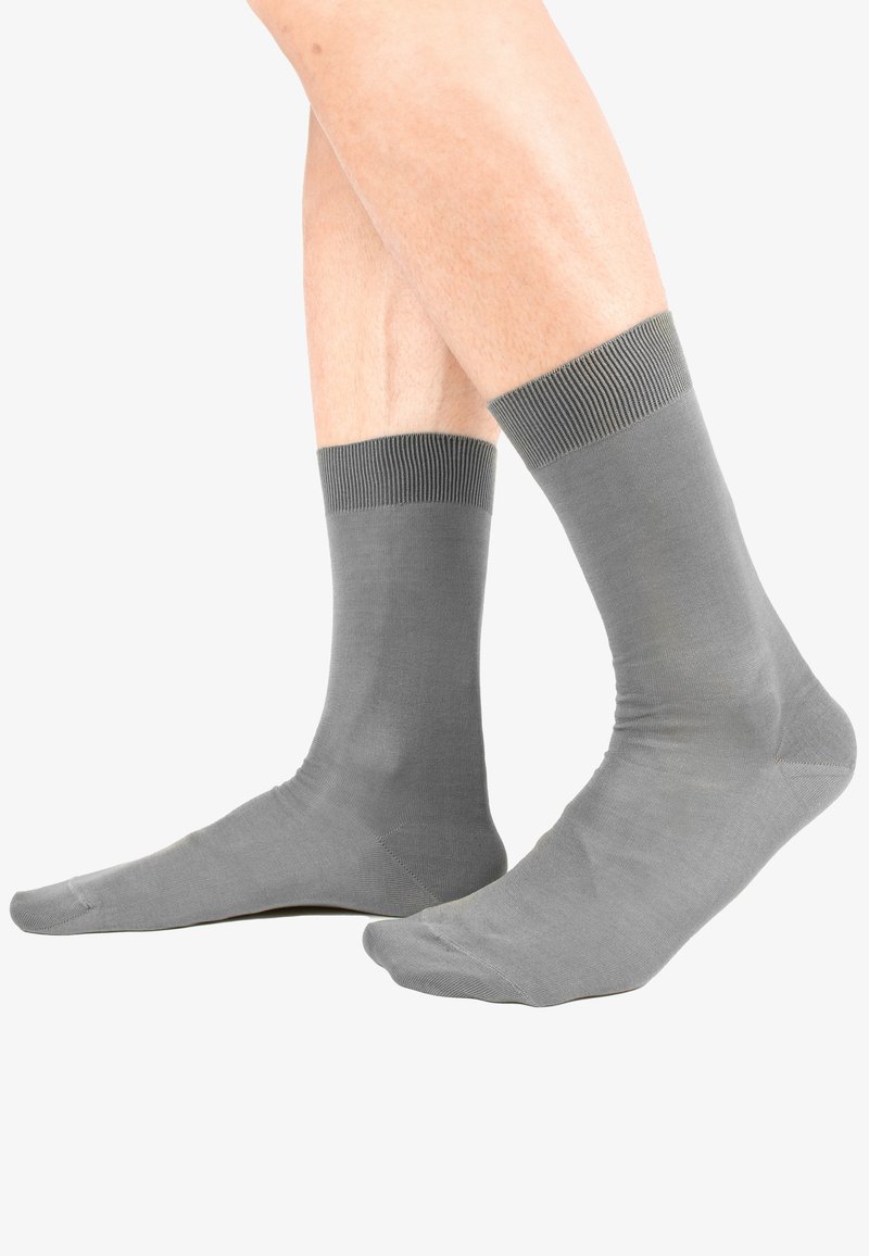 Calze grigie realizzate in un materiale liscio, con un polsino a coste. Il design è a lunghezza caviglia e presenta una punta senza cuciture.