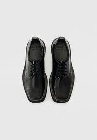 Zwarte lakleren schoenen met een slank ontwerp, voorzien van een ronde neus, vetersluiting en een gestructureerd interieur. Platte zolen.