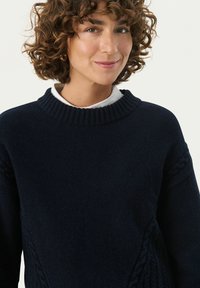 Navy knitted sweater with a ribbed round neckline and textured cable patterns on the sleeves, made of soft, warm material.