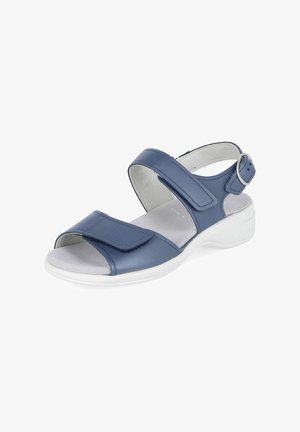 Sandale bleue à bout ouvert avec des brides Velcro réglables et une semelle blanche rembourrée, avec une boucle argentée sur la bride de cheville.