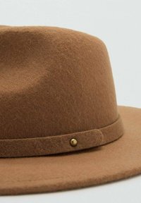 Cappello di feltro marrone con tesa larga, caratterizzato da una superficie strutturata e una banda decorativa con un piccolo dettaglio in metallo dorato.