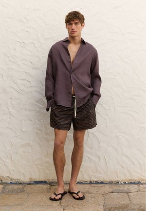 Lila Leinen-Hemd mit Knopfleiste, gemusterte schwarze Shorts und schwarze Flip-Flops. Glatte Textur, lässige Passform mit einem entspannten offenen Kragen.