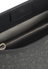 Interior de bolsa de cuero gris con un patrón texturizado, un bolsillo con cremallera y herrajes dorados, y un forro de tela suave.