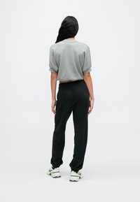 Γκρι cropped φούτερ με κοντά μανίκια, μαύρο στενό παντελόνι φόρμας με ελαστικές μανσέτες και ανοιχτόχρωμα αθλητικά παπούτσια.