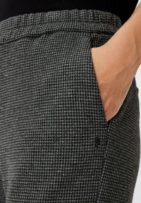 Gray check-patterned trousers featuring a ribbed waistband, side pockets, and a black metal logo accent on the hip.