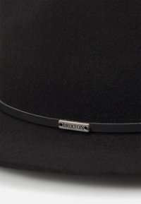 Black wool felt hat featuring a thin black band and a metallic label engraved with "BRIXTON," showcasing a smooth texture and structured shape.