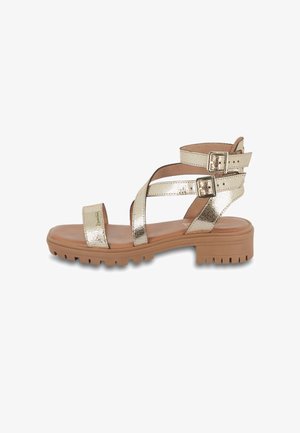 Sandalia de metal dorado con suela plana, que cuenta con múltiples correas ajustables y una plantilla texturizada para mayor comodidad. Hebillas en las correas del tobillo.