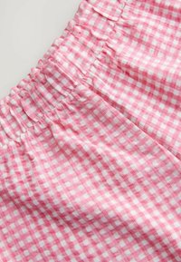 Tissu vichy rose et blanc avec une taille élastique froncée, présentant une surface texturée et un petit motif à carreaux.