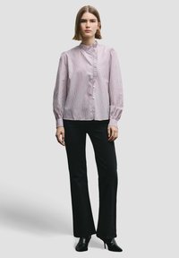 Light pink and white striped long-sleeve shirt with a high collar, button front, and gathered detailing. Paired with black flared pants and heels.