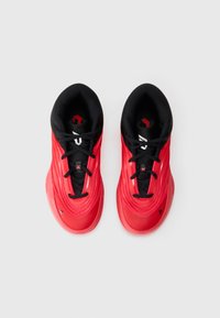 Une paire de baskets de sport rouges avec des lacets et un intérieur noirs, vue de dessus sur un fond blanc.
