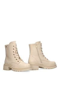 Botines beige con cordones en la parte delantera y cremallera lateral. Fabricados en material suave, con suela gruesa y acentos de hardware sutiles.