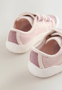 Paire de chaussures roses pour tout-petit en tissu doux, avec des bandes velcro et des semelles en caoutchouc blanc, vues de dos et de côté.