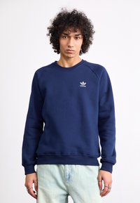 Mørkeblå sweatshirt lavet af en bomuldsblanding, med rund halsudskæring, ribbedeærmer og et lille hvidt adidas-logo på brystet.