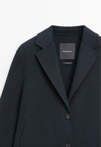 Cappotto in lana navy scuro con rever, design monopetto e tre bottoni. Etichetta visibile al centro. Trama liscia.