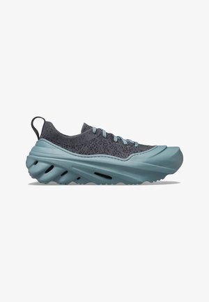Jasnoniebieski i ciemnoszary sportowy sneaker z grubą, teksturowaną podeszwą i dzianą cholewką, wyposażony w sznurowadła i pętlę na pięcie.