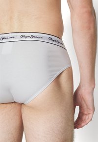 Weiße Unterhose mit einem schwarzen elastischen Bund, auf dem das Logo "Pepe Jeans" abgebildet ist. Der glatte, dehnbare Stoff passt sich der Körperform an.