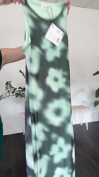Vestido longo com padrão floral em verde menta e preto. Feito de um tecido suave e leve, com um decote redondo e uma etiqueta pendurada.
