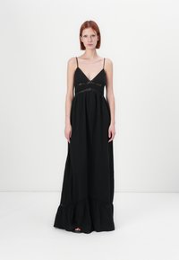 Svart maxi-kjole med tynne stropper, V-hals, blonde-detaljer i midjen, og en flytende kant med volangdetalj på bunnen.