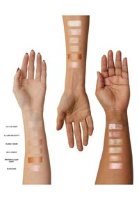 Färgprover av highlighter på armar; nyanserna varierar från blek vit till djup brons med en skimrande finish. Etiketter inkluderar namn på varje nyans.