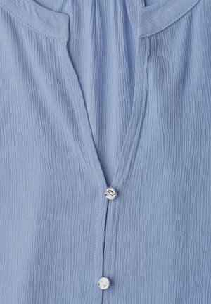 Lichtblauwe gestructureerde blouse met een V-hals en twee ronde zilveren knopen aan de voorkant.