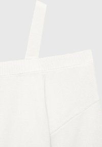 Vit off-shoulder topp med ribbad textur, slät stickad halsringning och ett hängande remdetalj på vänster sida.