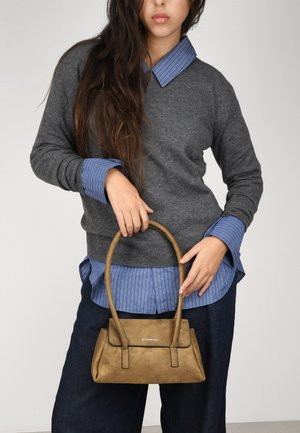 Bolso de piel ante color beige con un diseño estructurado y asas cortas. Lleva un suéter gris sobre una camisa de rayas azul, combinado con jeans oscuros.