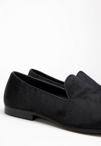 Czarne wsuwane buty z miękkiego materiału o gładkiej fakturze, z okrągłym noskiem i niskim, płaskim obcasem. Minimalistyczny design.
