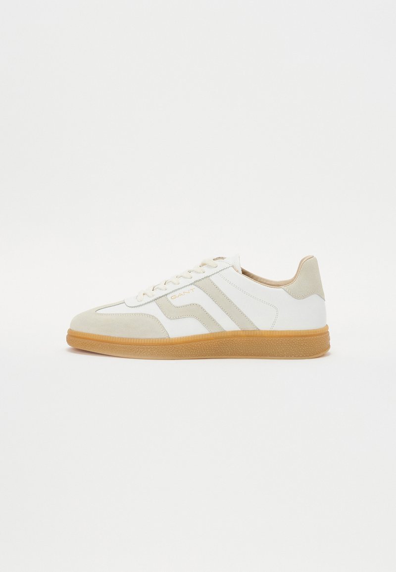 Adidași albi și crem din piele și suede, cu un toc din cauciuc, trei dungi diagonale și detaliu cu logo pe lateral.