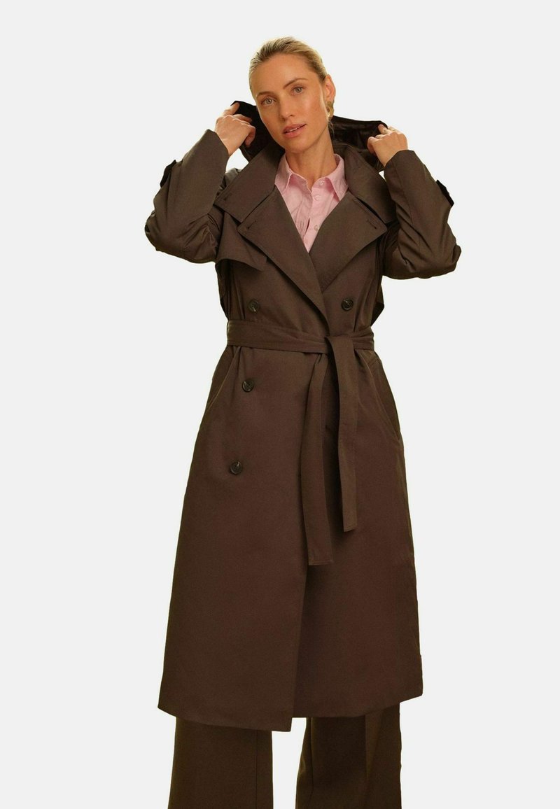 Rjavi plašč z dvojnim zapenjanjem, širokimi ovratniki in pasom, ki se veže, z dolgimi rokavi in gumbi.