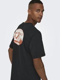 Zwart katoenen T-shirt met een groot oranje en wit bergafbeelding op de achterkant. Standaard pasvorm met korte mouwen en ronde hals.