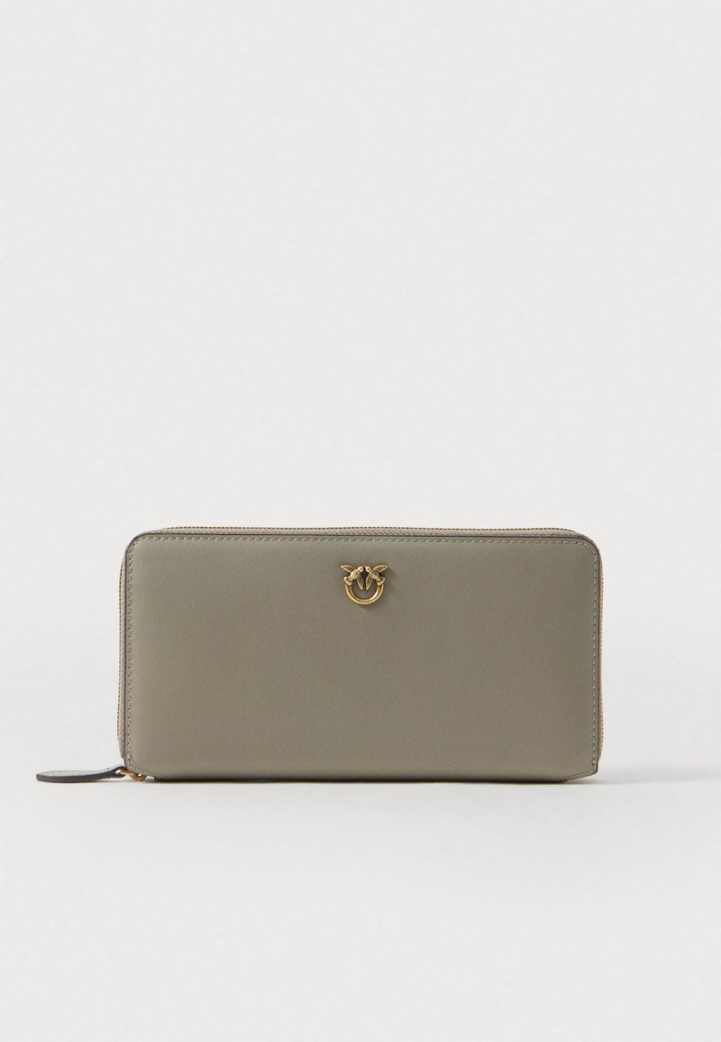 Cartera de cuero verde mate con herrajes en tono dorado. Presenta un cierre con cremallera y un logo decorativo en relieve en la parte frontal. Forma rectangular.