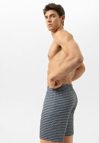 Navyblauwe zwembroek met een wit golfpatroon, gemaakt van lichtgewicht stof. Voorzien van een elastische tailleband en zijnaden.