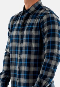 Flanellen shirt in marineblauw, grijs en blauw ruitpatroon. Voorzien van een button-down kraag, lange mouwen en een borstzak. Zachte textuur.