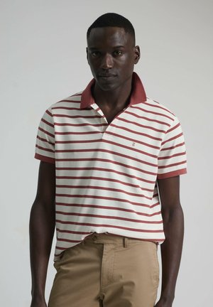 Polo de rayas en color crema y burdeos, con un cuello burdeos sólido. Mangas cortas y un diseño de corte ajustado, combinado con pantalones beige.