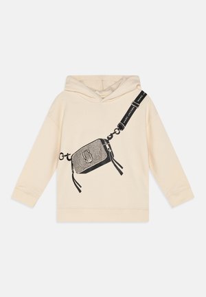 Felpa crema con una grafica di una piccola borsa nera, dotata di dettagli in catena e frange. Il design include un accento con un logo audace.