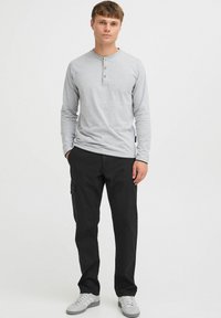 Grey long-sleeve henley shirt with three button placket, paired with black cargo pants featuring side pockets and gray sneakers.