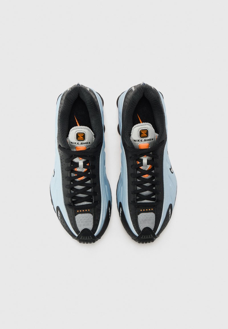 Buty Nike Shox z czarną i jasnoniebieską cholewką, teksturą siateczkową, wyraźnym sznurowaniem, pomarańczowymi akcentami oraz charakterystycznym wzorem podeszwy.